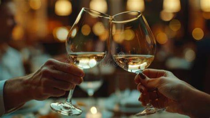 People clinking glasses in wine taste as they celebrate a birthday party in backyard